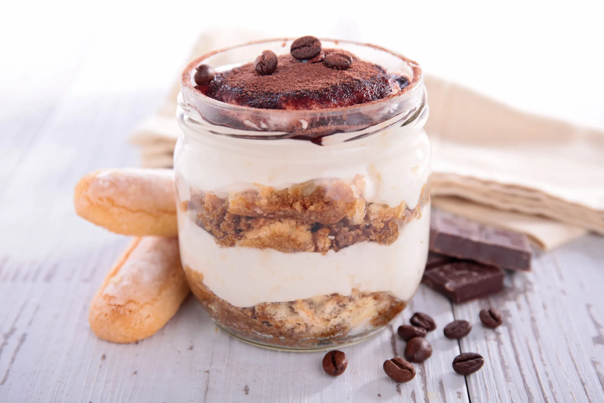 Tiramisù in vasetto di vetro con strati di crema, savoiardi e cacao
