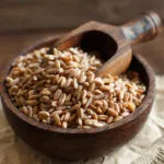 Farro perlato crudo in una ciotola di legno con paletta