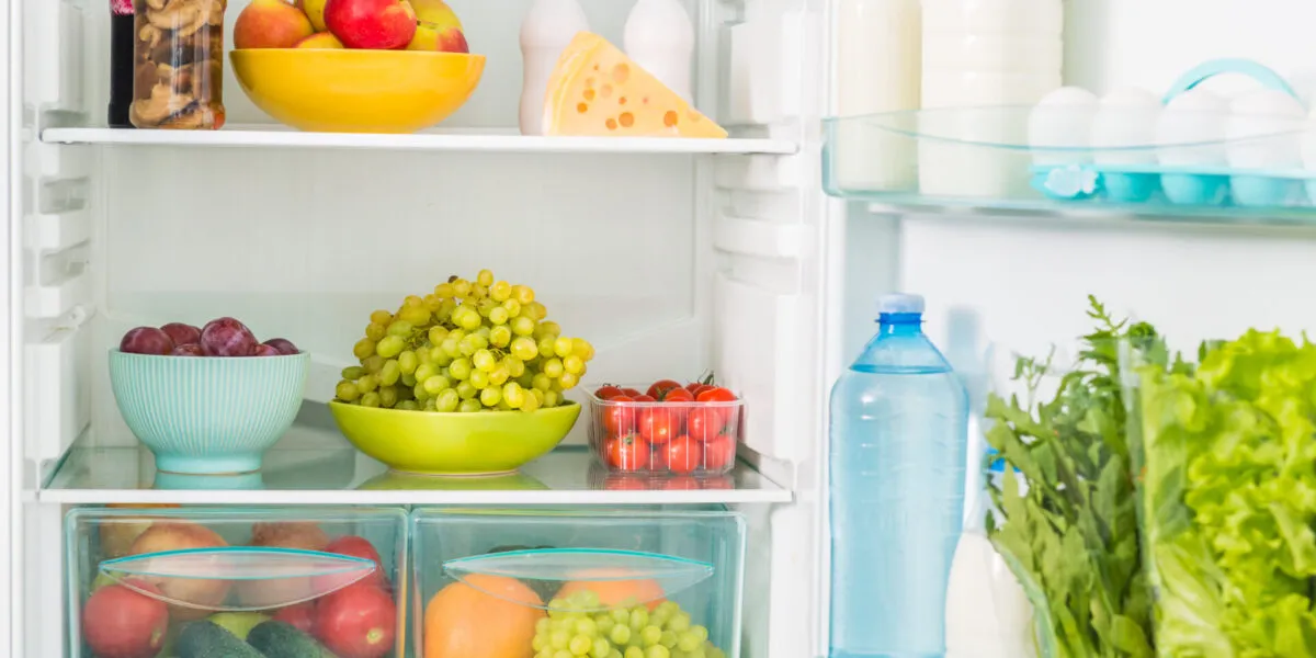 Interno di un frigorifero con frutta, latticini e verdure sui ripiani