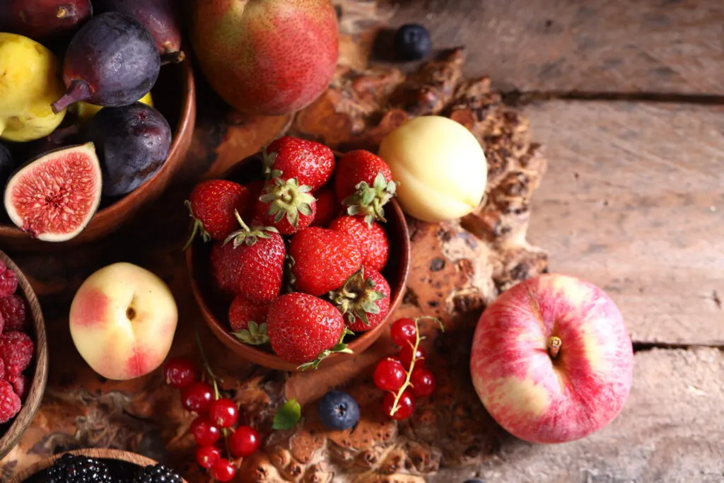 Frutta fresca di stagione in ciotole di legno su un tavolo rustico