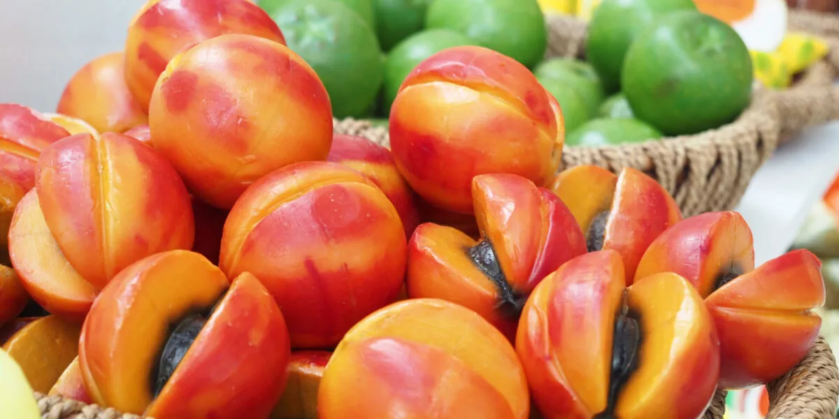 Cesti di vimini pieni di frutta martorana modellata a forma di pesche e albicocche, alcune tagliate a metà, in una pasticceria siciliana
