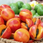 Cesti di vimini pieni di frutta martorana modellata a forma di pesche e albicocche, alcune tagliate a metà, in una pasticceria siciliana