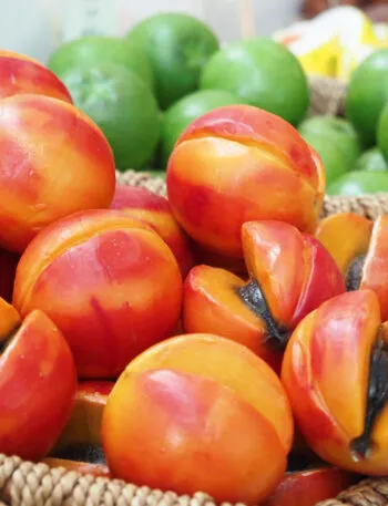 Cesti di vimini pieni di frutta martorana modellata a forma di pesche e albicocche, alcune tagliate a metà, in una pasticceria siciliana