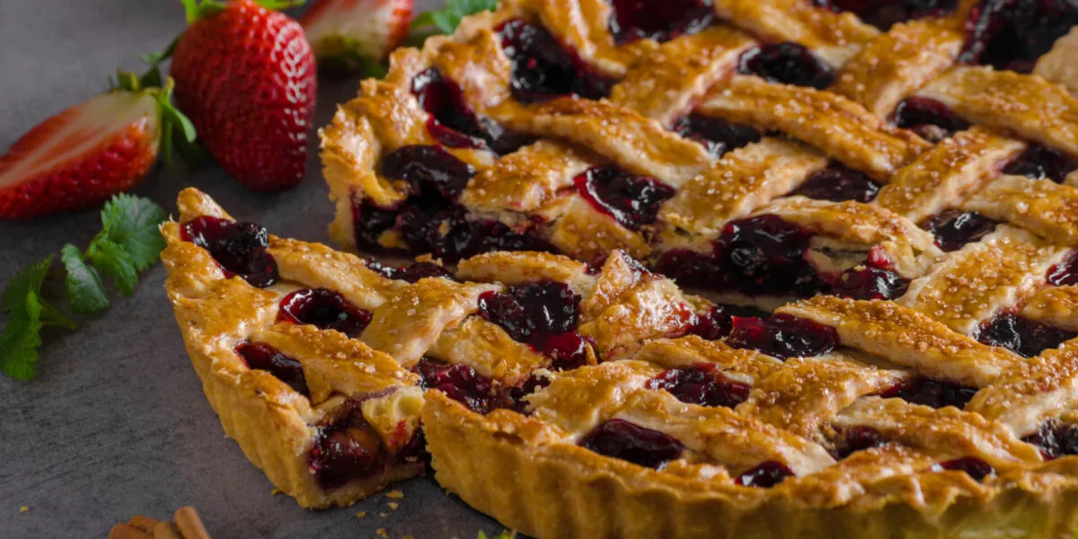 Crostata ai frutti rossi con grata di frolla e una fetta tagliata
