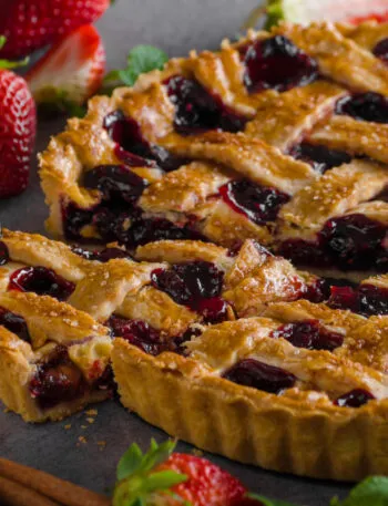 Crostata ai frutti rossi con grata di frolla e una fetta tagliata
