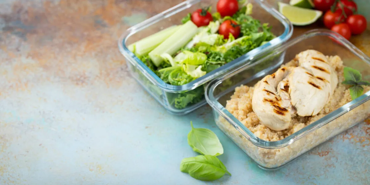 Contenitori di vetro con pollo grigliato, quinoa e insalata