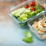 Contenitori di vetro con pollo grigliato, quinoa e insalata