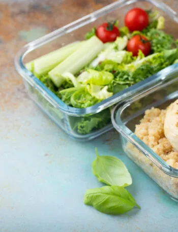 Contenitori di vetro con pollo grigliato, quinoa e insalata