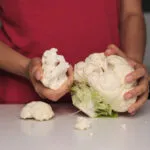 Mani che staccano le cimette da un cavolfiore fresco