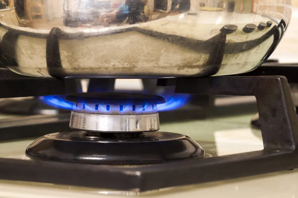 Fiamma blu bassa di un fornello a gas sotto il fondo di una pentola, senza fuoriuscire dai bordi