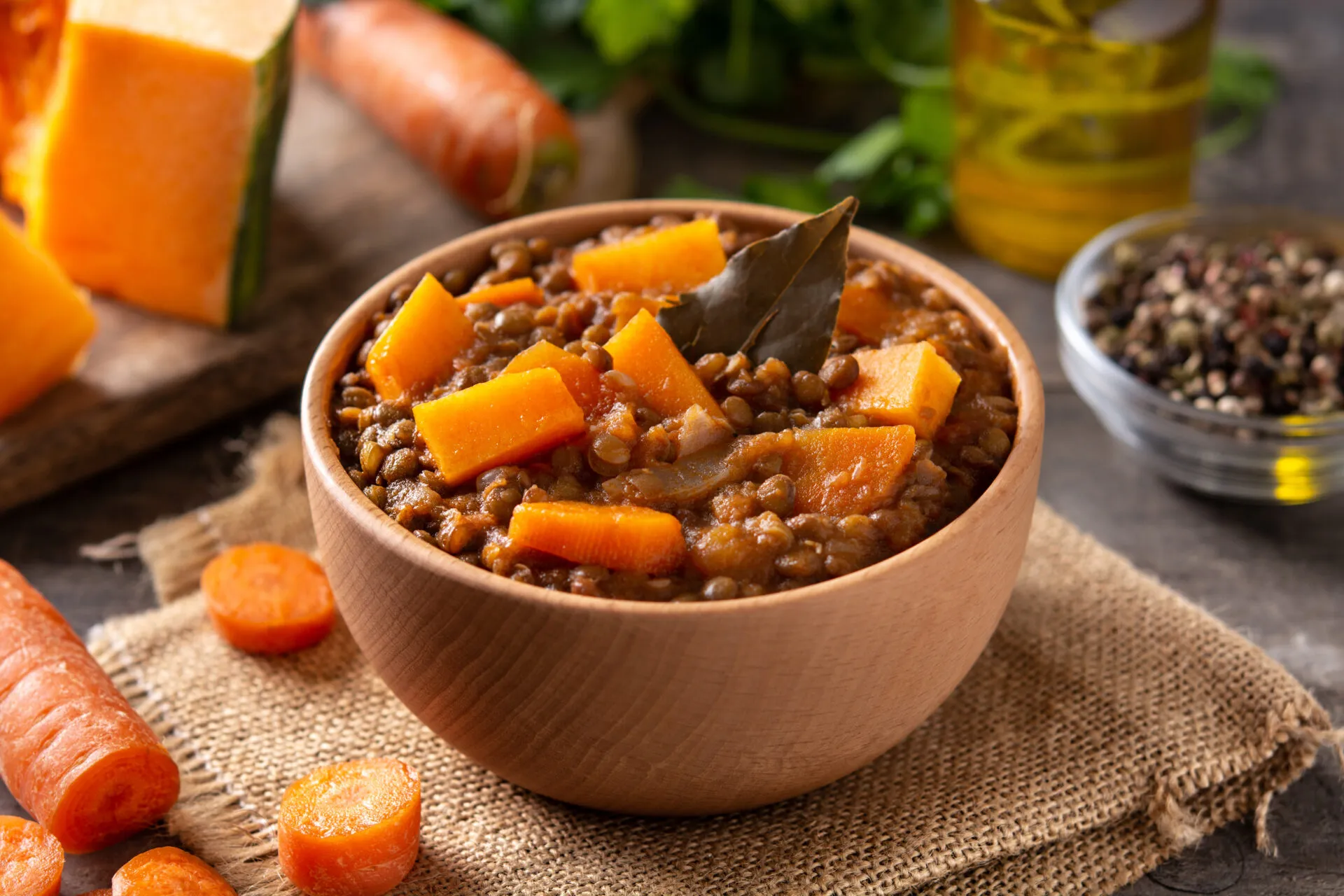 Ciotola di minestra di zucca e lenticchie con cubetti di zucca, lenticchie intere e una foglia di alloro