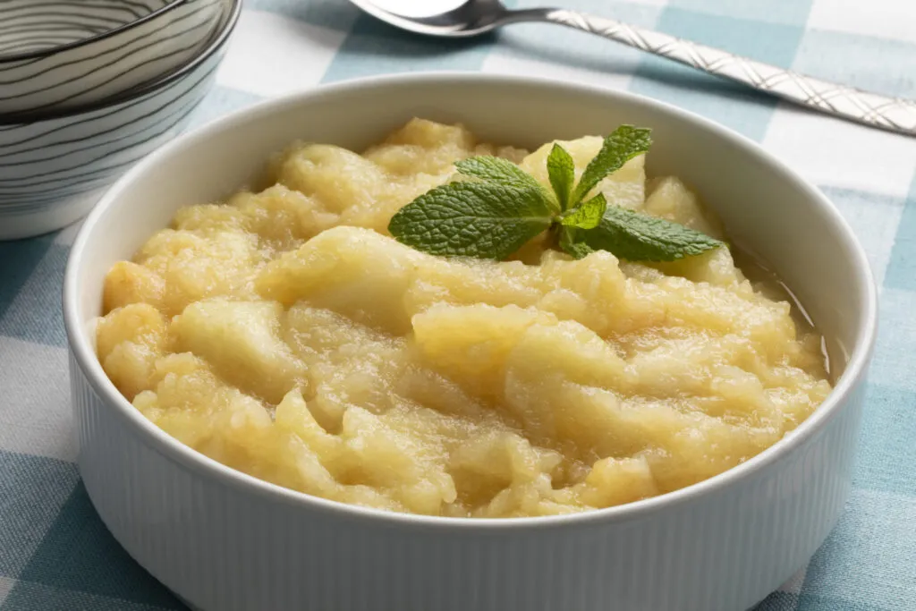 Purea di mele in una ciotola bianca con foglie di menta