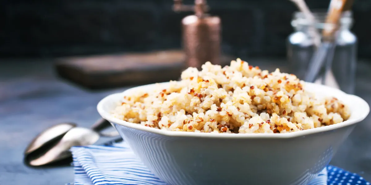 Ciotola bianca di quinoa cotta e sgranata, mista bianca e rossa, con i chicchi ben separati