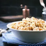 Ciotola bianca di quinoa cotta e sgranata, mista bianca e rossa, con i chicchi ben separati