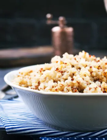 Ciotola bianca di quinoa cotta e sgranata, mista bianca e rossa, con i chicchi ben separati