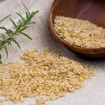 Riso integrale crudo in una ciotola di legno con rosmarino