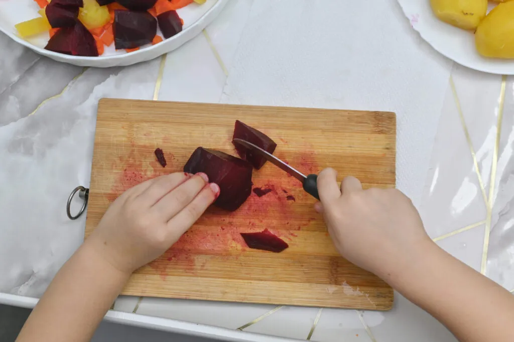 Tagliere di legno macchiato di rosso dal succo di barbabietola, con i segni dei tagli precedenti sulla superficie