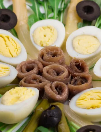 Uova sode tagliate a metà in un'insalata con acciughe e olive