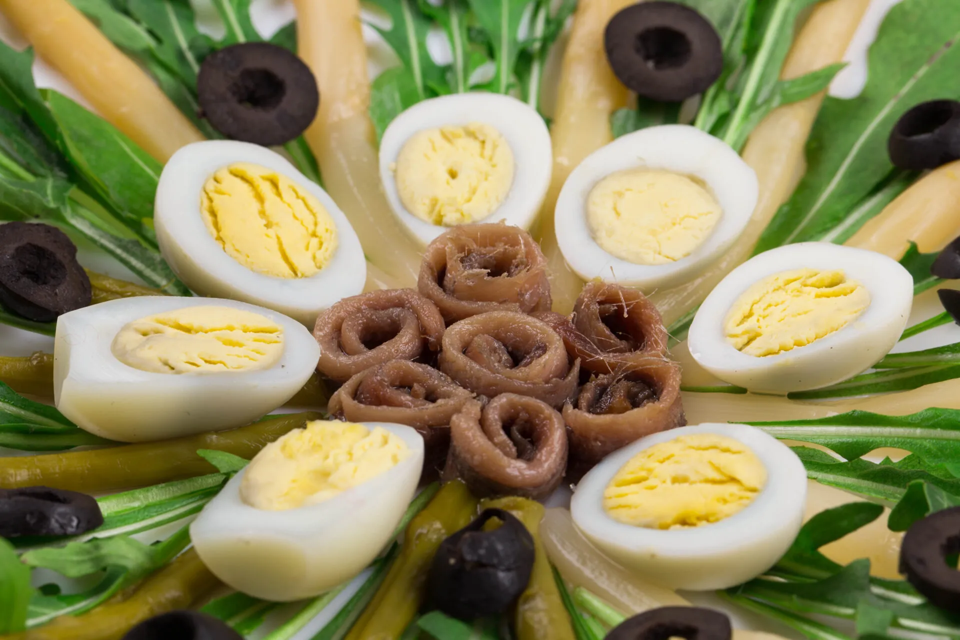 Uova sode tagliate a metà in un'insalata con acciughe e olive