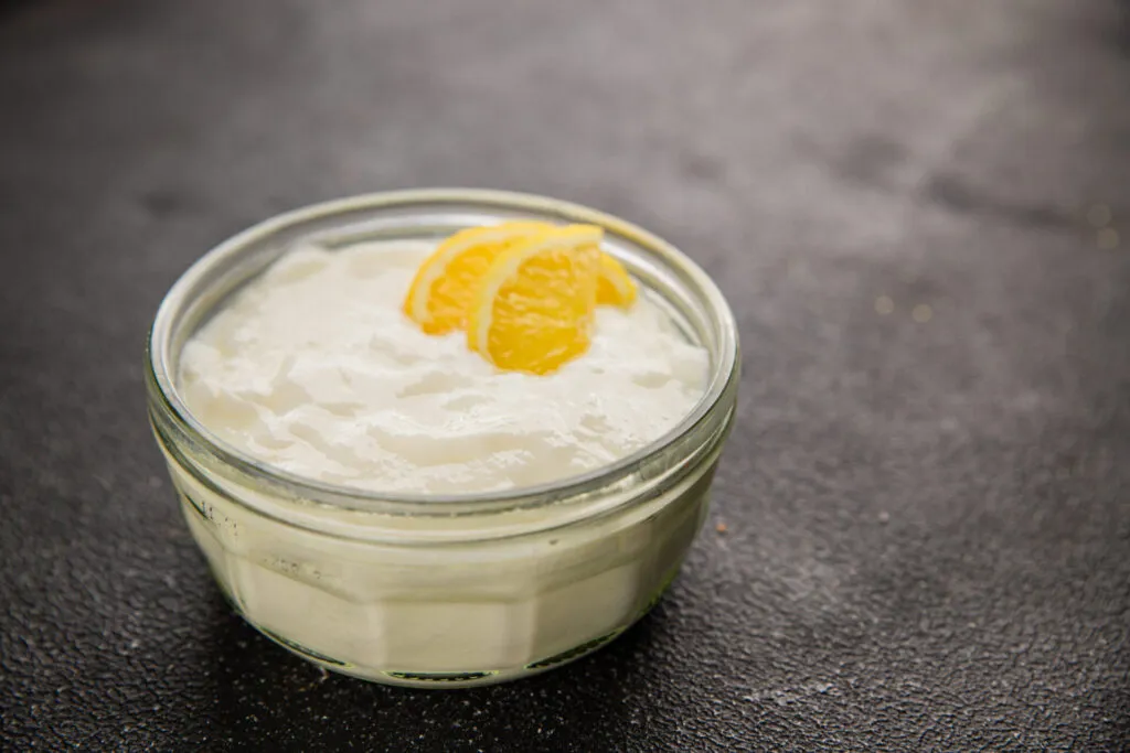 Yogurt greco denso in una ciotolina di vetro con scorza di limone