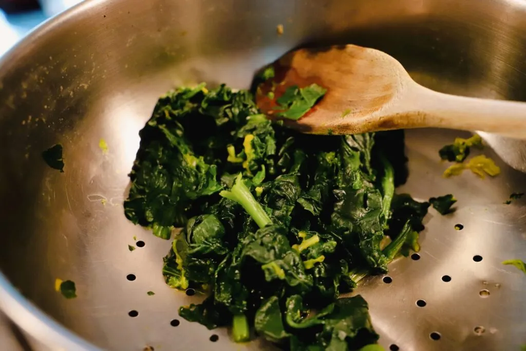 Cime di rapa cotte con foglie e gambi teneri, scolate e mescolate con un cucchiaio di legno