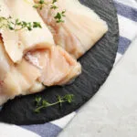Tranci di baccalà dissalato con rametti di timo su un piatto di ardesia