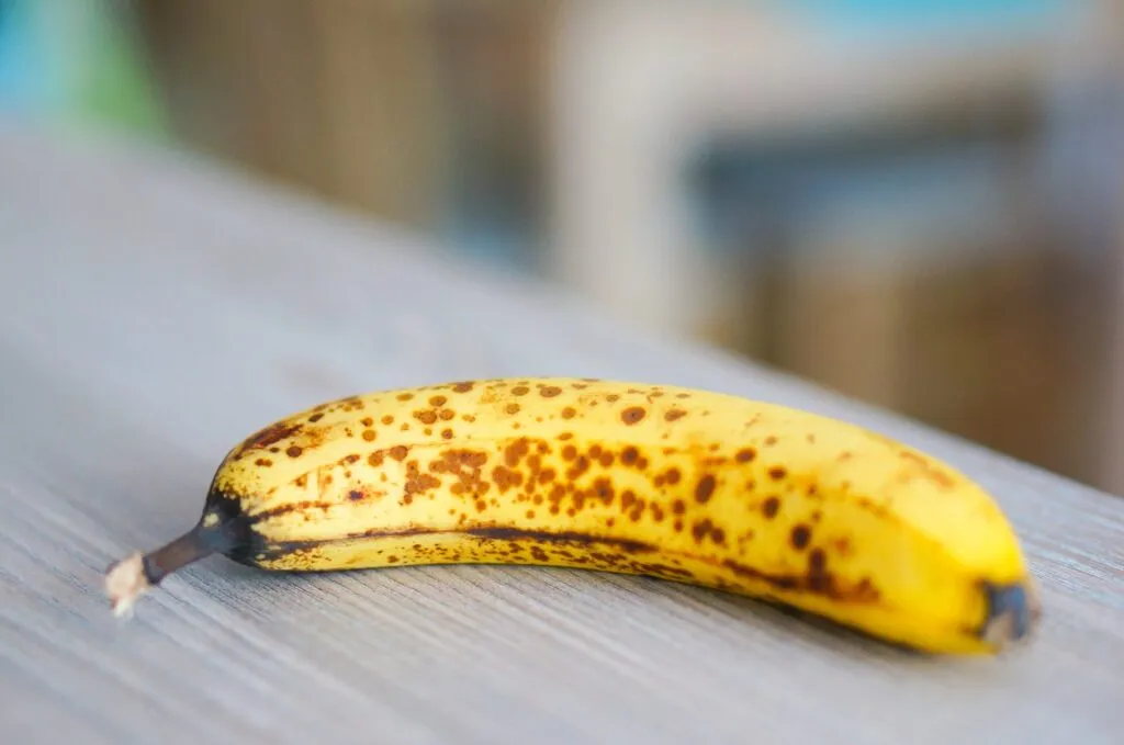 Banana gialla con la buccia coperta di piccole macchie marroni, segno di piena maturazione