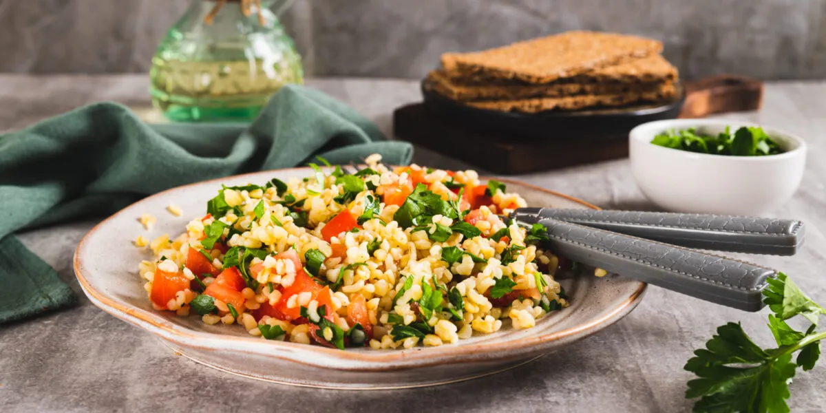 Insalata di bulgur con pomodori a cubetti e prezzemolo fresco in un piatto di ceramica