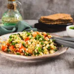 Insalata di bulgur con pomodori a cubetti e prezzemolo fresco in un piatto di ceramica