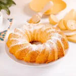 Ciambella intera spolverizzata di zucchero a velo con caffè e limoni sul tavolo della colazione