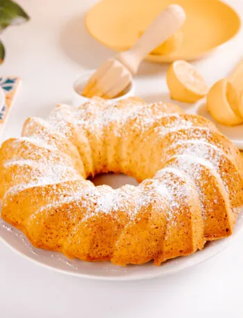 Ciambella intera spolverizzata di zucchero a velo con caffè e limoni sul tavolo della colazione