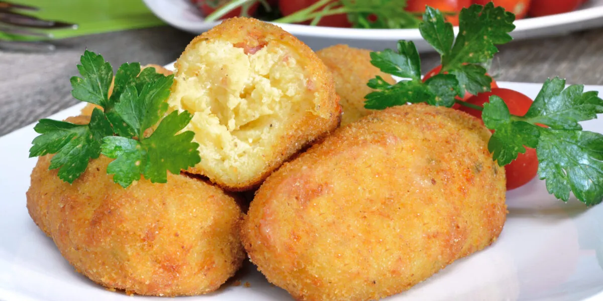 Crocchette di patate dorate con una spezzata a metà che mostra l’interno morbido
