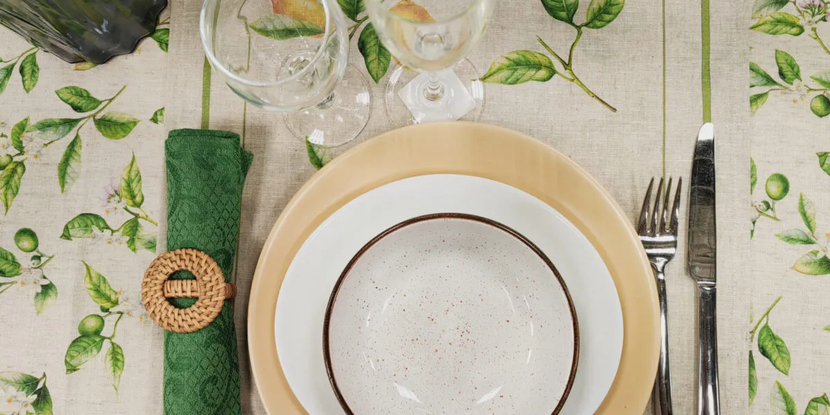 Tavola apparecchiata per una persona con tovaglia a limoni, piatti in ceramica e tovagliolo verde