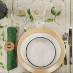 Tavola apparecchiata per una persona con tovaglia a limoni, piatti in ceramica e tovagliolo verde