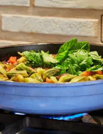Padella troppo piena di verdure e pomodoro che cuociono nel loro liquido sul fornello acceso