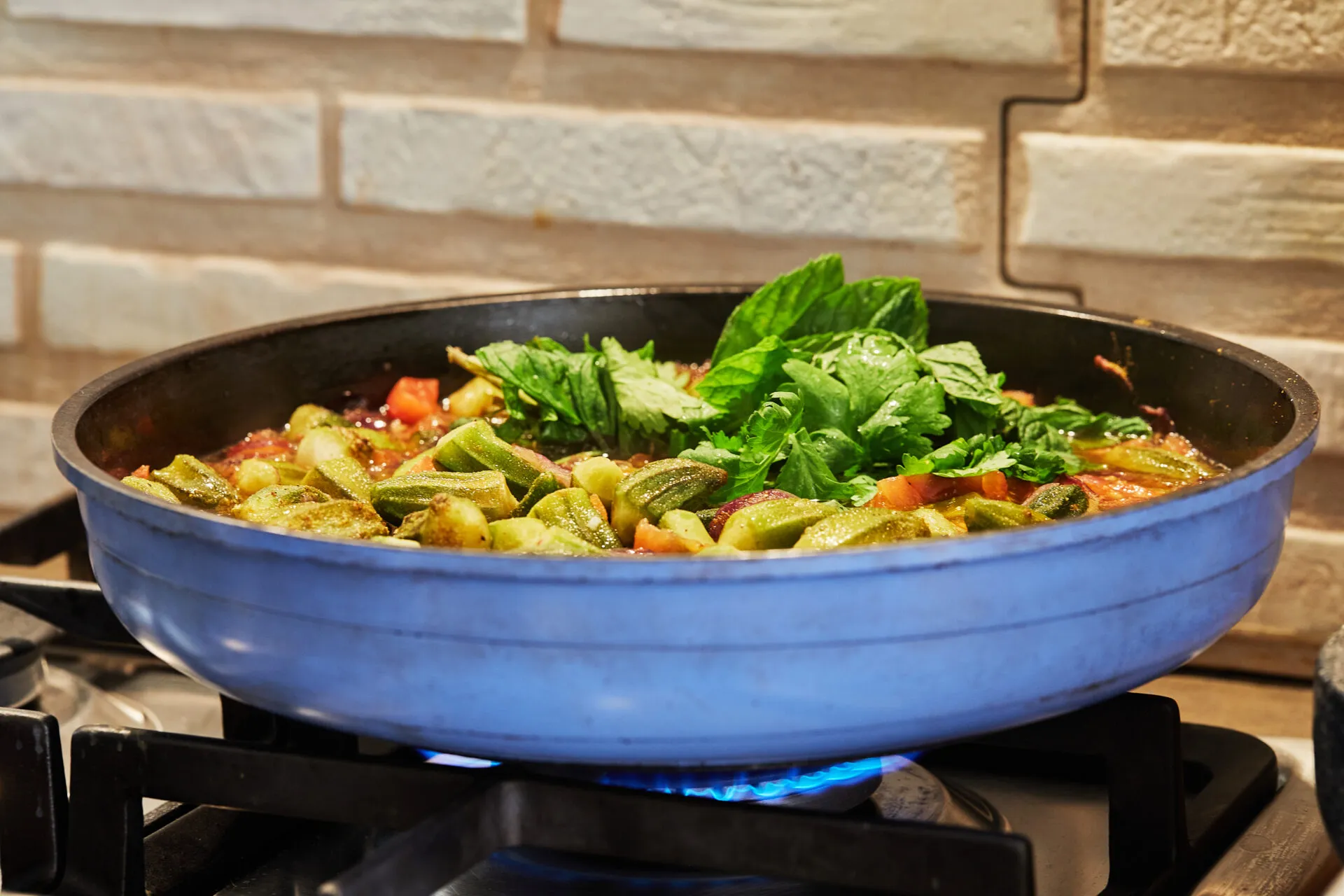 Padella troppo piena di verdure e pomodoro che cuociono nel loro liquido sul fornello acceso