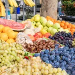 Banco di frutta autunnale al mercato con uva, prugne, castagne, mele e mandarini