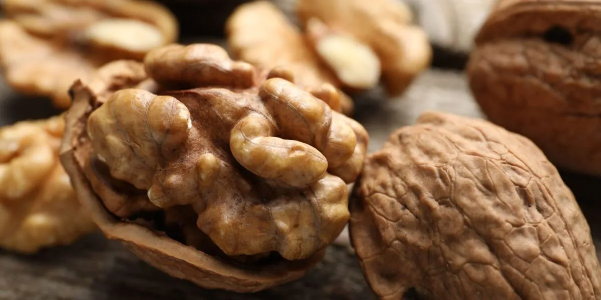 Gheriglio di noce nel mezzo guscio con altre noci intere e sgusciate su un tavolo di legno