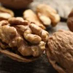Gheriglio di noce nel mezzo guscio con altre noci intere e sgusciate su un tavolo di legno