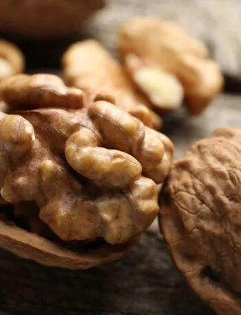 Gheriglio di noce nel mezzo guscio con altre noci intere e sgusciate su un tavolo di legno
