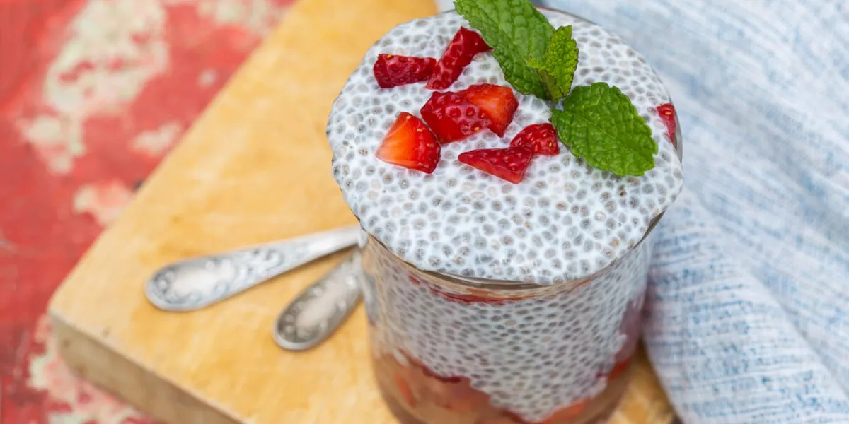 Chia pudding in vasetto di vetro con fragole a pezzetti e foglie di menta