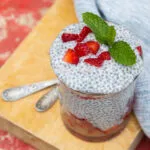 Chia pudding in vasetto di vetro con fragole a pezzetti e foglie di menta