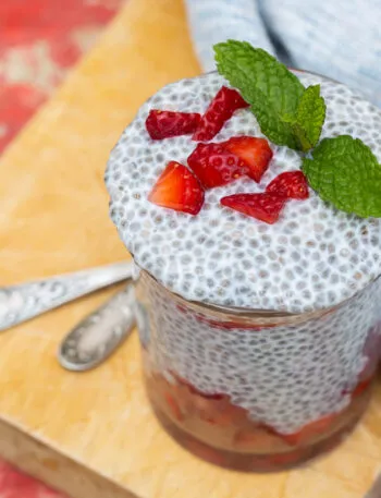 Chia pudding in vasetto di vetro con fragole a pezzetti e foglie di menta