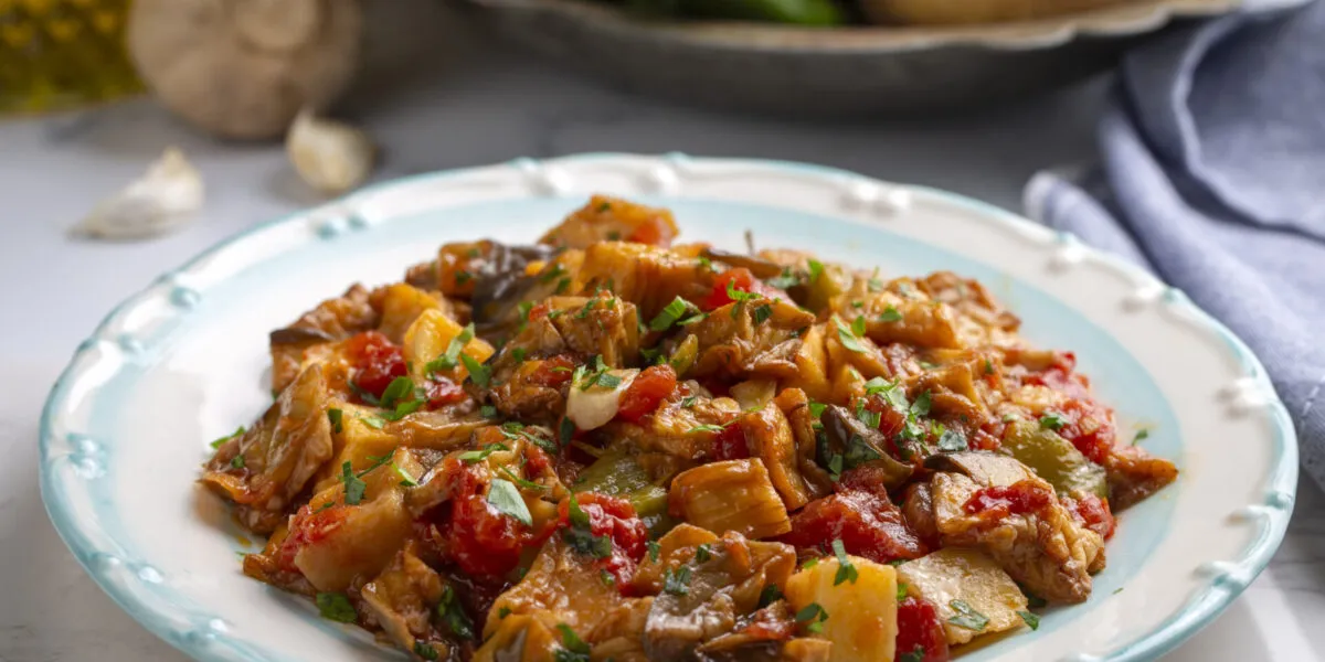 Piatto di funghi, patate, peperoni e pomodoro cotti in umido con prezzemolo fresco
