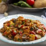 Piatto di funghi, patate, peperoni e pomodoro cotti in umido con prezzemolo fresco