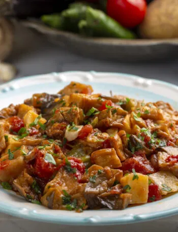 Piatto di funghi, patate, peperoni e pomodoro cotti in umido con prezzemolo fresco